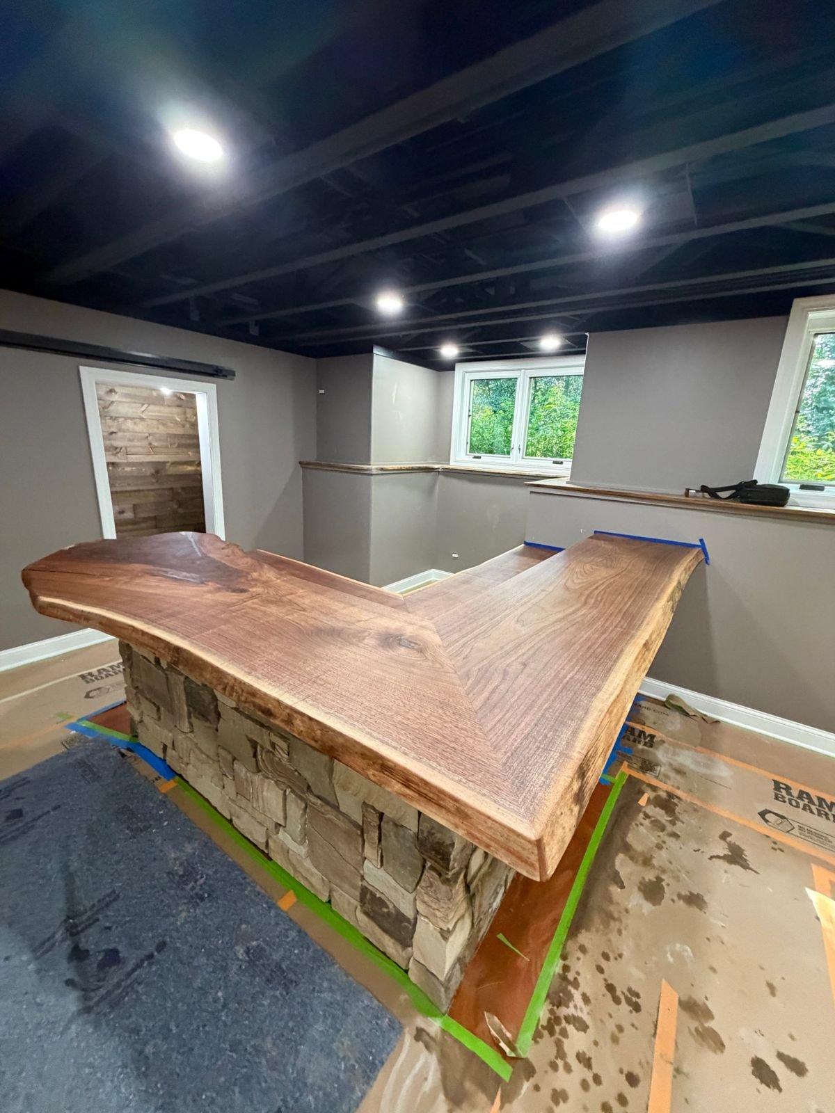 L-shaped live edge walnut bar on a stacked stone base