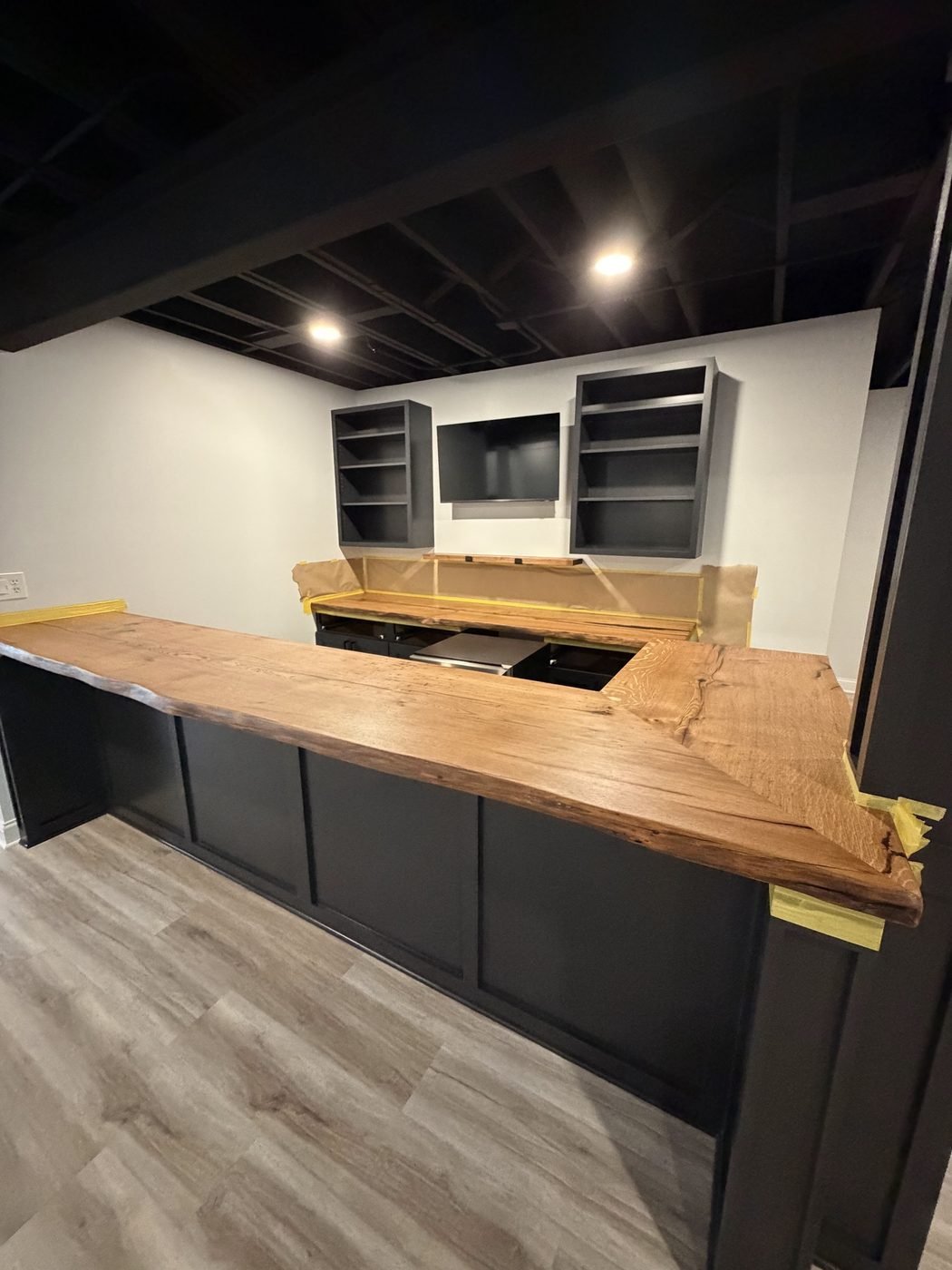 L-shaped solid wood bar and back bar on black cabinets