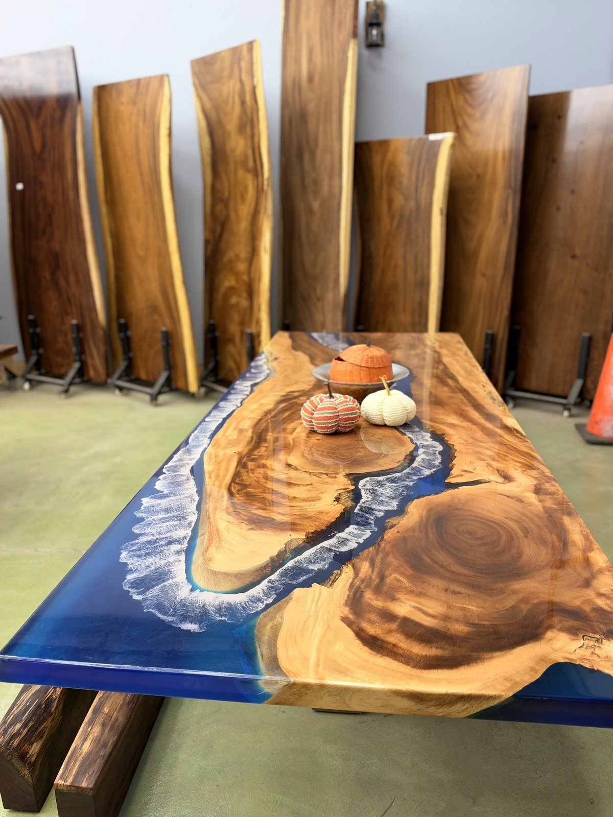 Blue epoxy river table with live edge slabs standing behind it